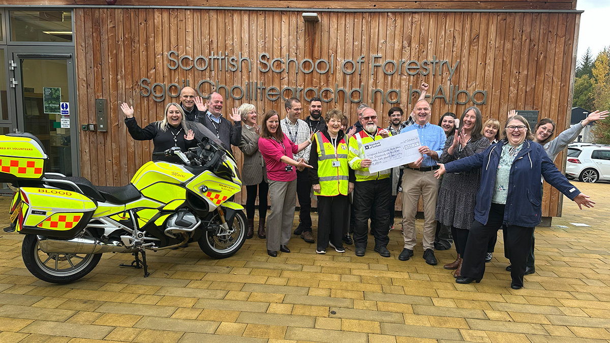 Big group of people holding a cheque and laughing